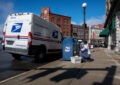 Letter carrier works near blue collection box