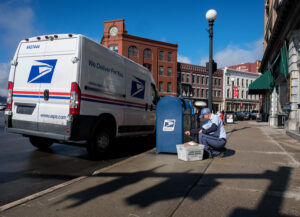 Letter carrier works near blue collection box