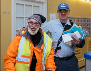 Letter carrier places arm around smiling man