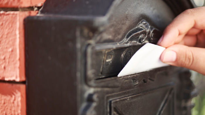 Hand inserting letter into mailbox