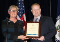 Woman hands man plaque on stage