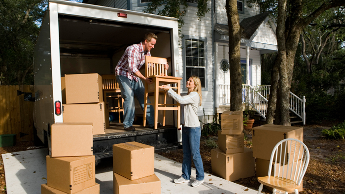Man, woman carrying furniture out of moving van