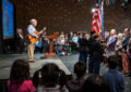 Joe Negri stands on stage playing guitar