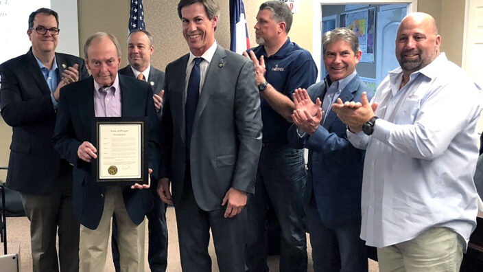 People gather around man holding certificate