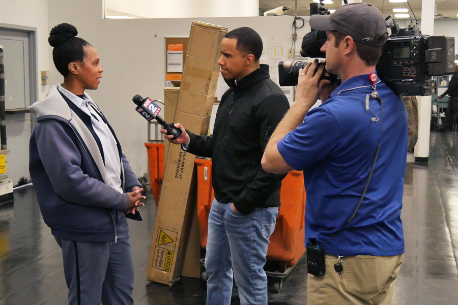 Postal worker is interviewed by TV news crew in Post Office work room