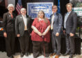 Five people stand in front of United States Air Mail stamp poster