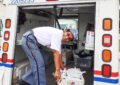 Smiling postal worker stands in back of delivery vehicle, sorting bags of food