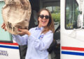 Postal worker holds up brown paper bag