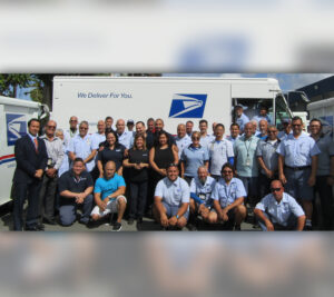 Postal workers pose in front of delivery vehicle