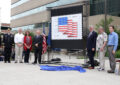 People stand next to stamp poster