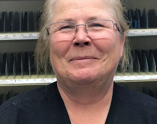 Smiling postal worker stands in Post Office sorting area