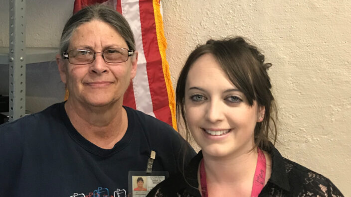 Smiling Rural Carrier and Retail Associate in front of U.S. flag