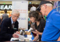 Two customers purchase stamps at USPS retail booth