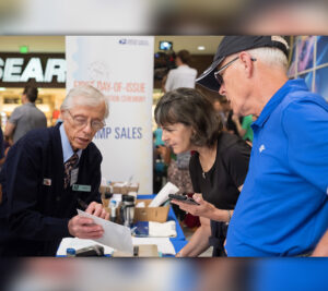 Two customers purchase stamps at USPS retail booth