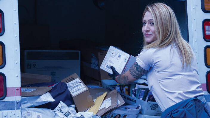 Postal worker loads delivery vehicle