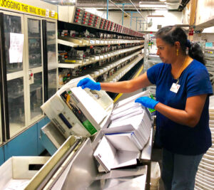 Woman works on sorting machine inside postal plant