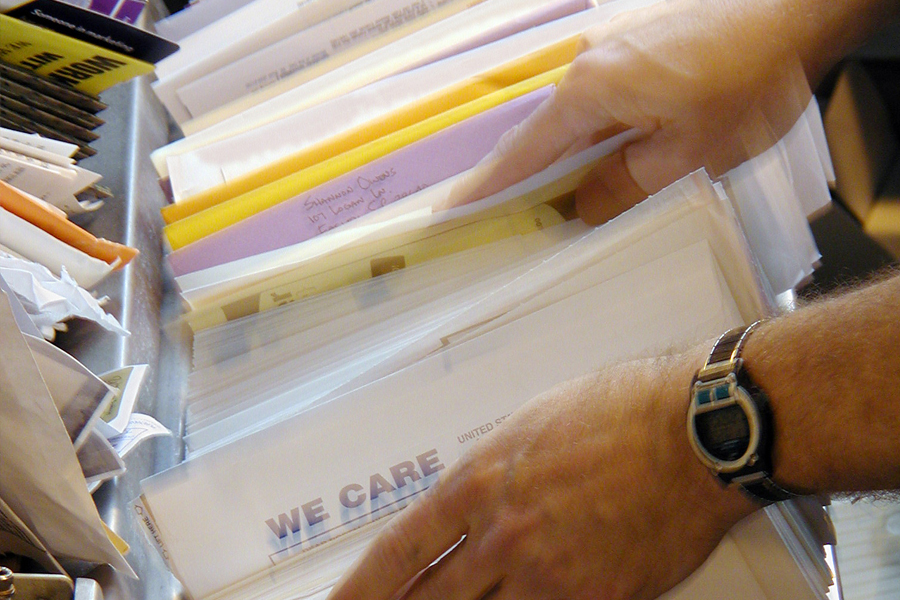 Hands sorting mail in postal workroom