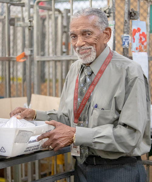Smiling postal worker holds mail tray