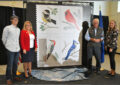 Smiling group of people stand near stamp display