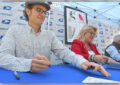 Man, woman sit at table, signing event programs