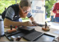 Postal retail worker places hand stamp on envelope