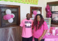 Postal employees stand next to breast cancer awareness display