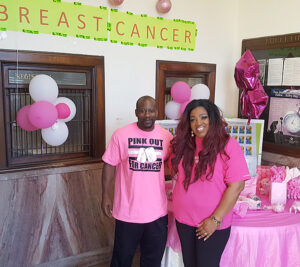 Postal employees stand next to breast cancer awareness display
