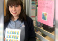 Smiling postal worker holds up stamp sheets