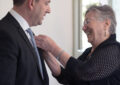 Smiling woman fastens pin to man's lapel