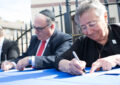 People sit at table, signing programs