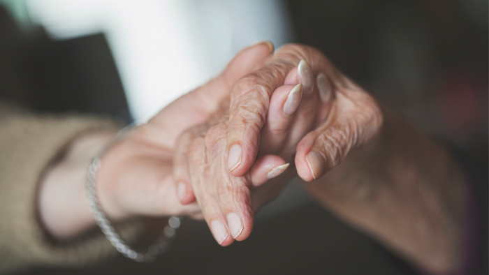 Hand of a younger person holding hand on an older person