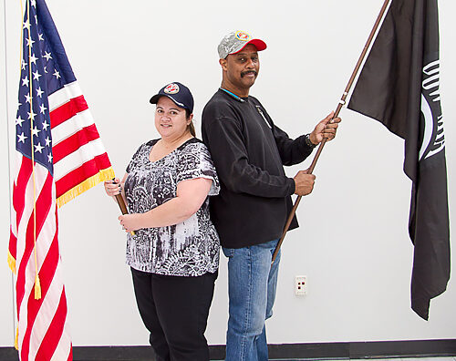 Two employees hold U.S. and POW-MIA flags