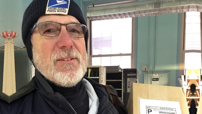 Letter carrier stands in postal work room