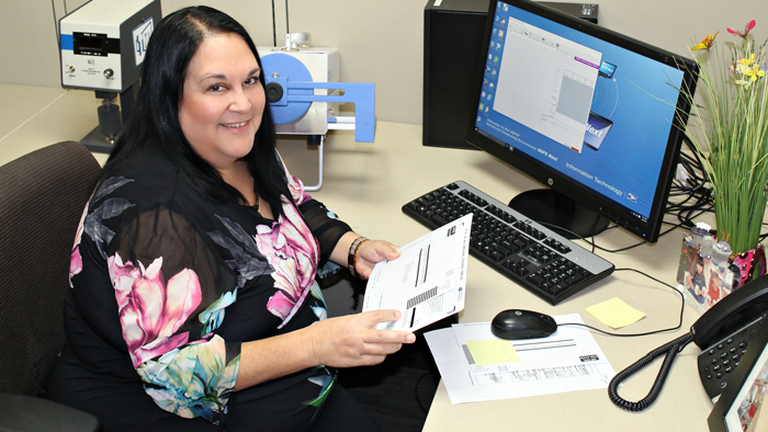 Pacific Area Mailpiece Design Analyst Paula Bigornia sitting at desk