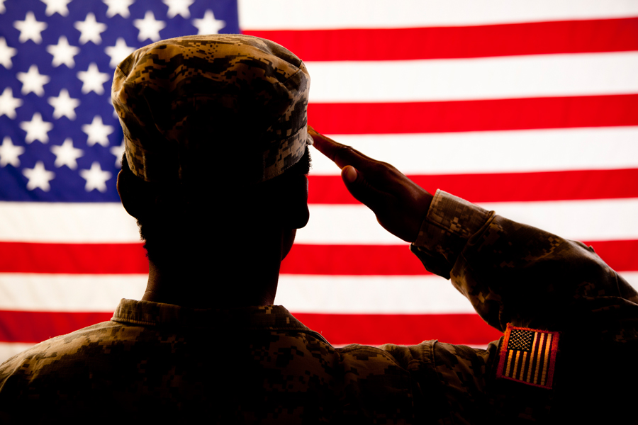 Man in military uniform salutes U.S. flag