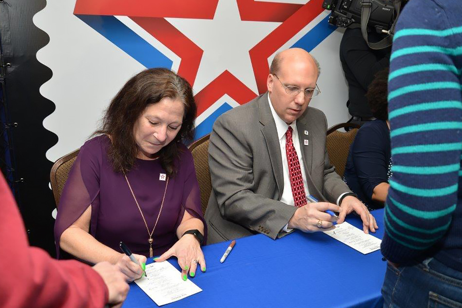 Woman, man sit at table signing documents