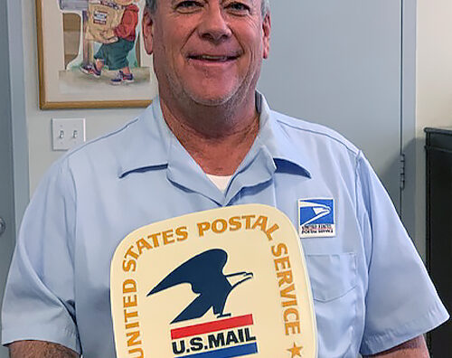 Smiling letter carrier holds vintage postal logo