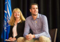 Smiling woman, man sit on stage