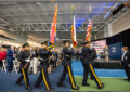 Police officers in dress uniforms carry flags in formation