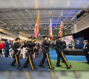 Police officers in dress uniforms carry flags in formation