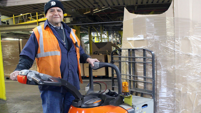 Detroit Mail Handler Michael Mendez stands near equipment