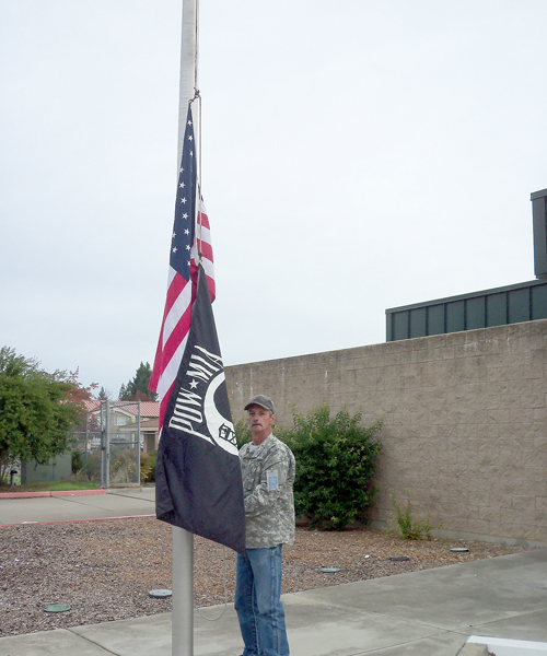 Randy Lane, a custodian, raising the U.S. and POW-MIA flags.