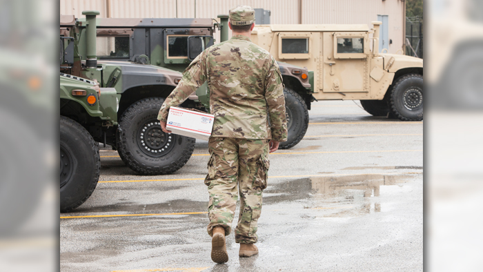 Serviceman carries a USPS package