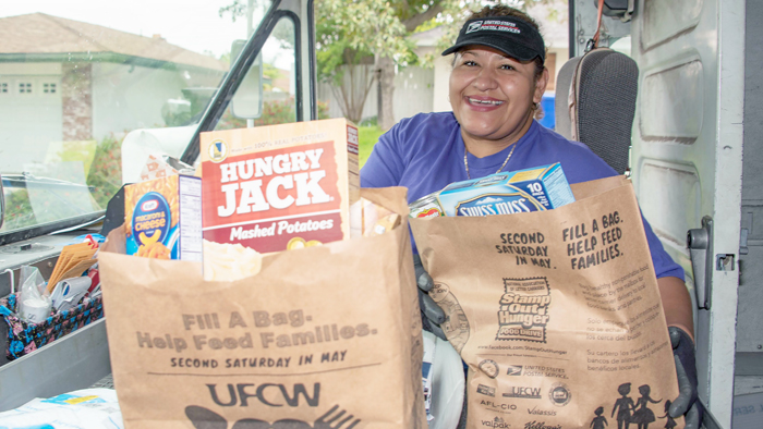 Postal Service employee with food donated for Stamp Out Hunger drive