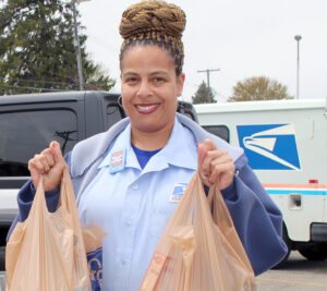 Smiling letter carrier holds two bags of food