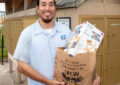 Smiling letter carrier holds grocery bag