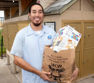 Smiling letter carrier holds grocery bag