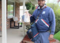 Smiling letter carrier holds bag full of food