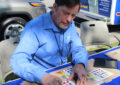 Postal worker sits at table, handling stamp sheets