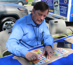 Postal worker sits at table, handling stamp sheets